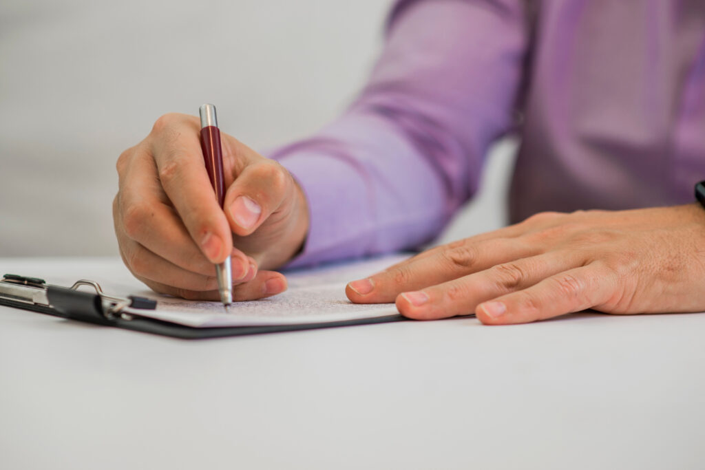 Man holding a pencil, writing on a paper