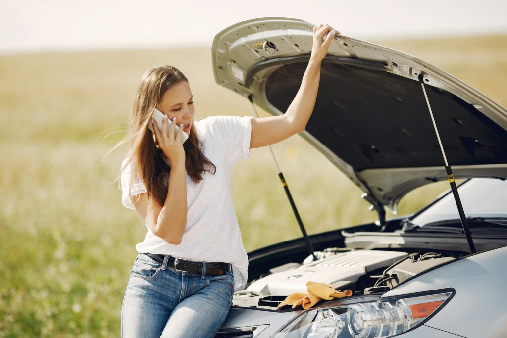 Woman using smartphone near broken automobile 